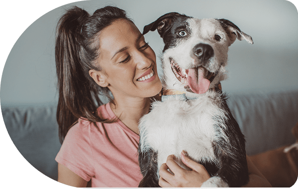 Woman happily hugs her joyful dog indoors.